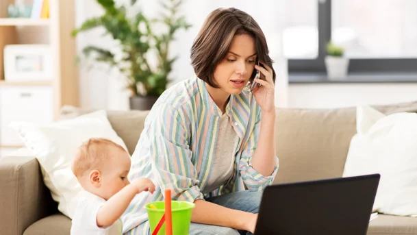working-mom-talks-on-the-phone-while-her-baby-plays-nearby
